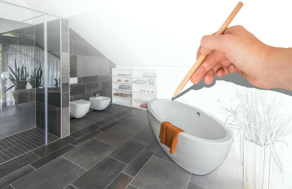 Eine Hand mit einem Bleistift skizziert ein modernes Badezimmerdesign mit einer Mischung aus Realität und Zeichnung. Zur Ausstattung gehören eine Glasdusche, eine freistehende Badewanne und ein gefliester Boden.