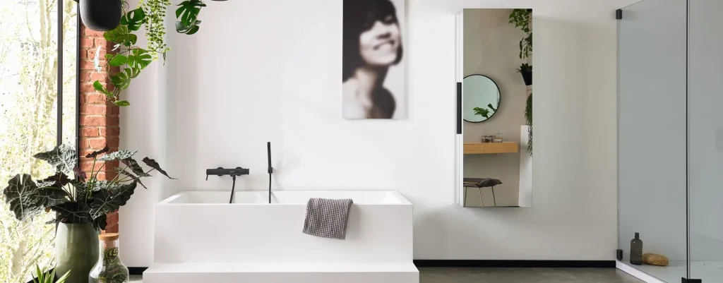 Modernes Badezimmer mit weißer Badewanne, schwarzem Wasserhahn und grauem Handtuch. Darüber hängt ein unscharfes Porträt. Grüne Pflanzen und minimalistisches Dekor sorgen für Frische.
